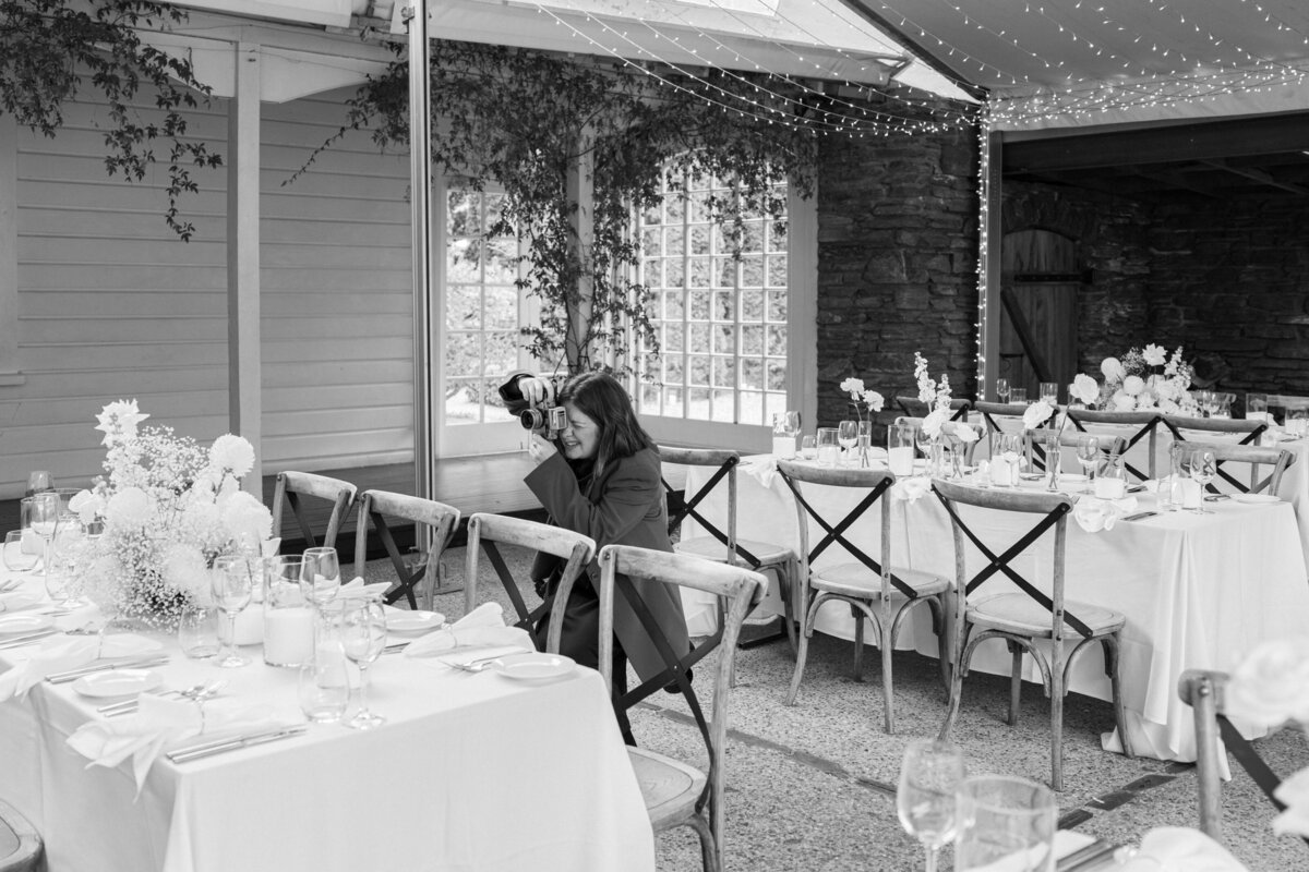 black and white image of photographer taking a details photo in a beautiful reception room