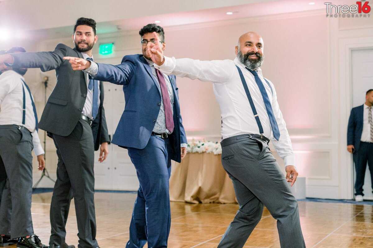 Groom and two groomsmen perform a traditional Indian wedding dance