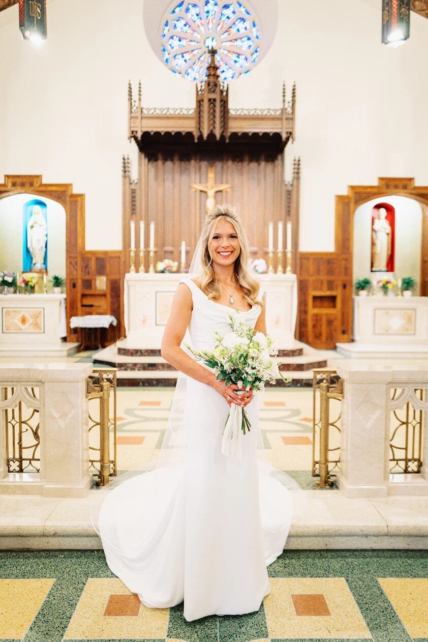 A bride stands in front of an altar at a catholic church