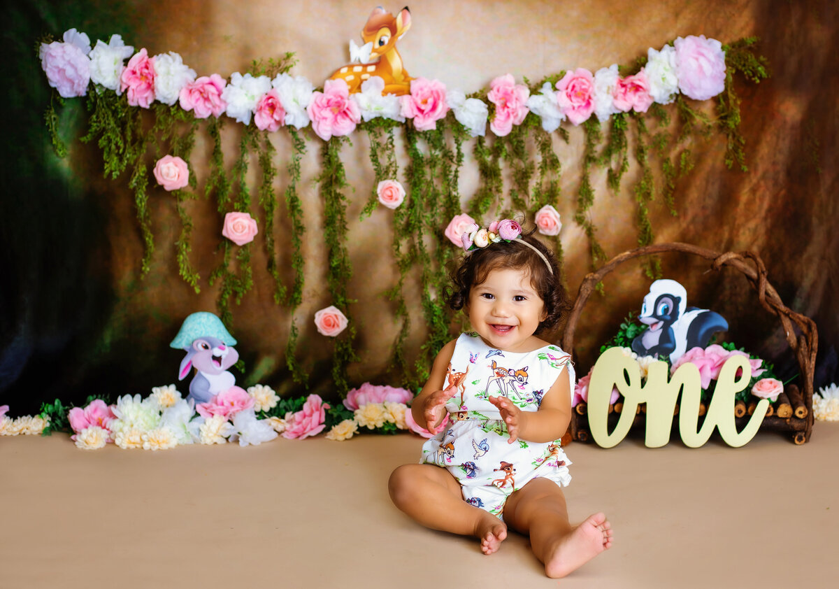 Cake Smash Photographer, a baby girl smiles and claps for her one year old birthday