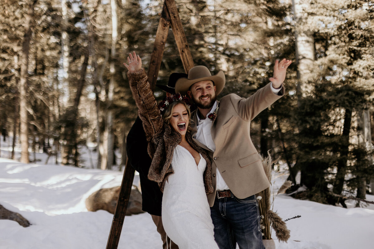 bride and groom right after their ceremony cheering in the snow