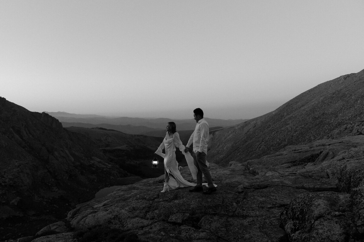 Couple holds lantern walking on the mountain tops in colorado