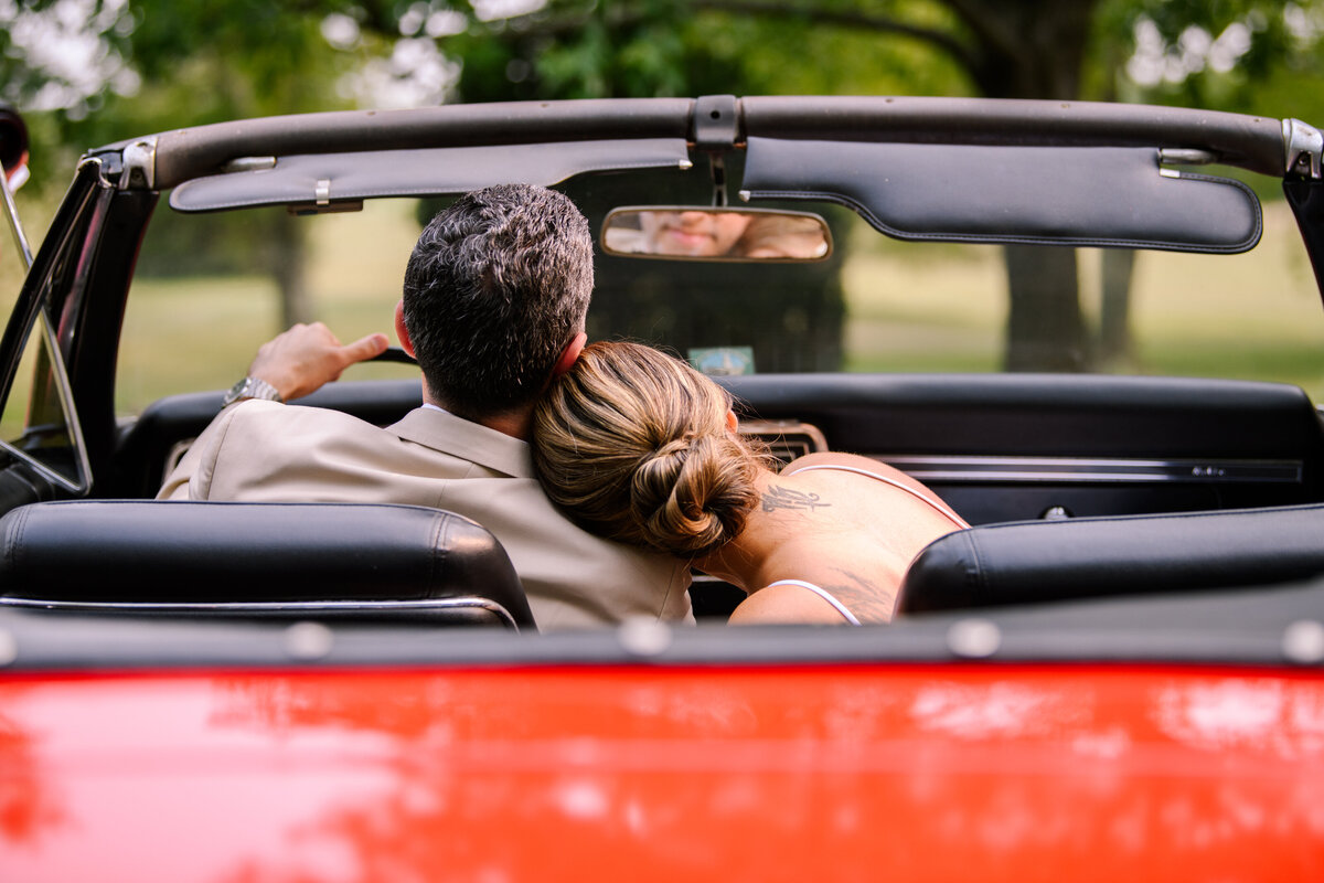 Bride leaning on Groom in convertible