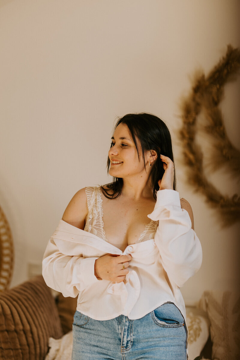 Séance photo portrait d'une jeune femme brune, chemise blanche tombant sur les épaules laissant apercevoir de la lingerie dans un décor cosy.