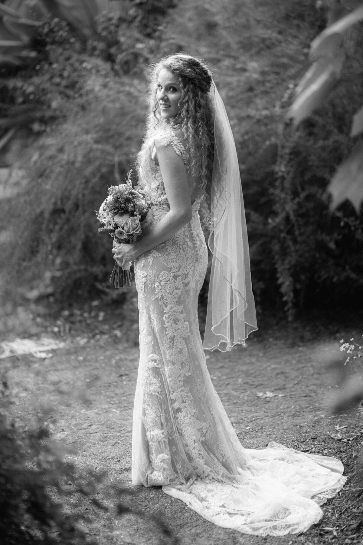 A bride holding a bouquet of flowers looking over one shoulder