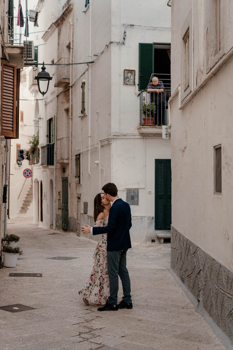 Séance photo de mariage en Italie, dans les ruelles blanches de Monopoli, avec un couple marchant main dans la main.