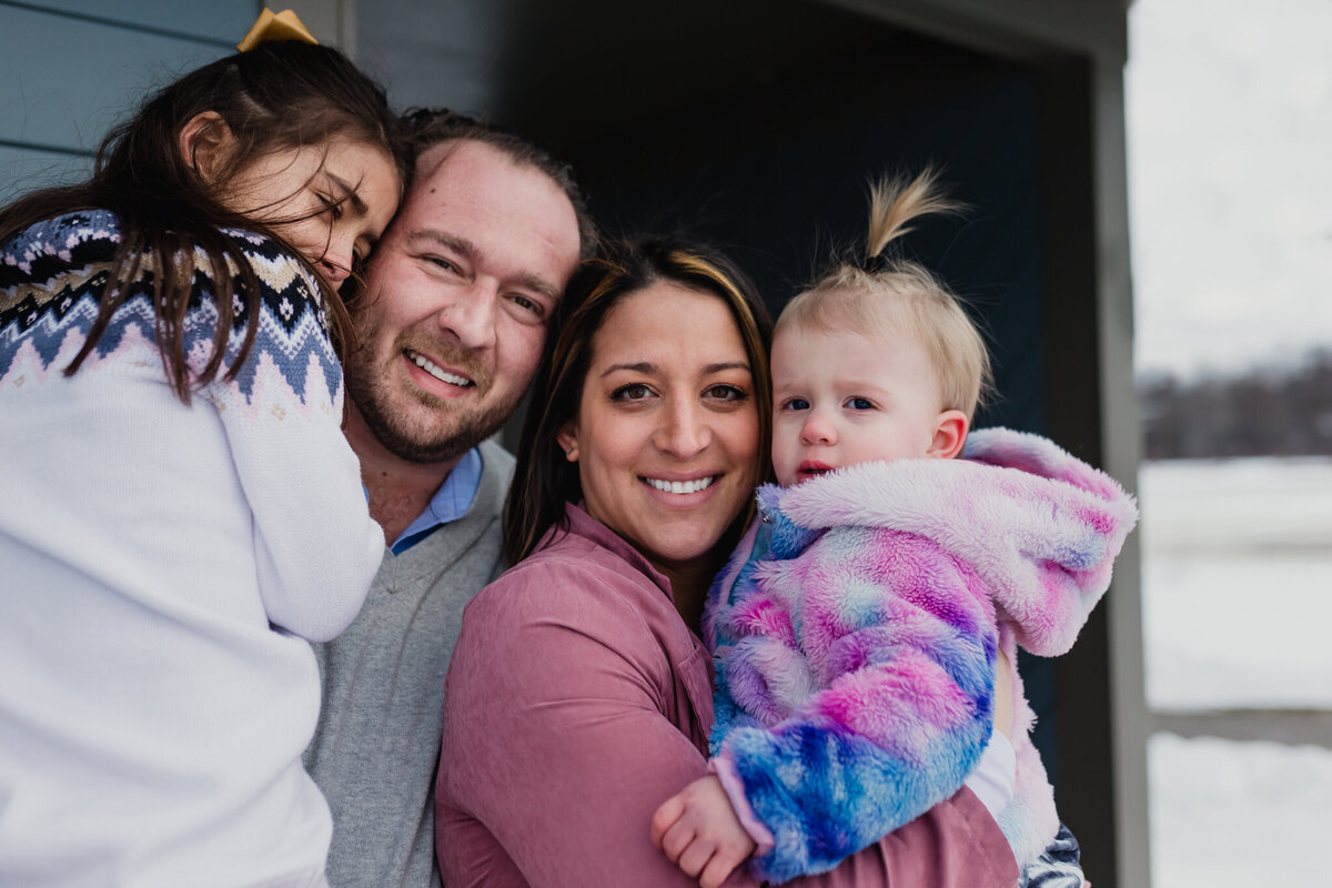 Family photo with a mom and dad holding their two young daughters.