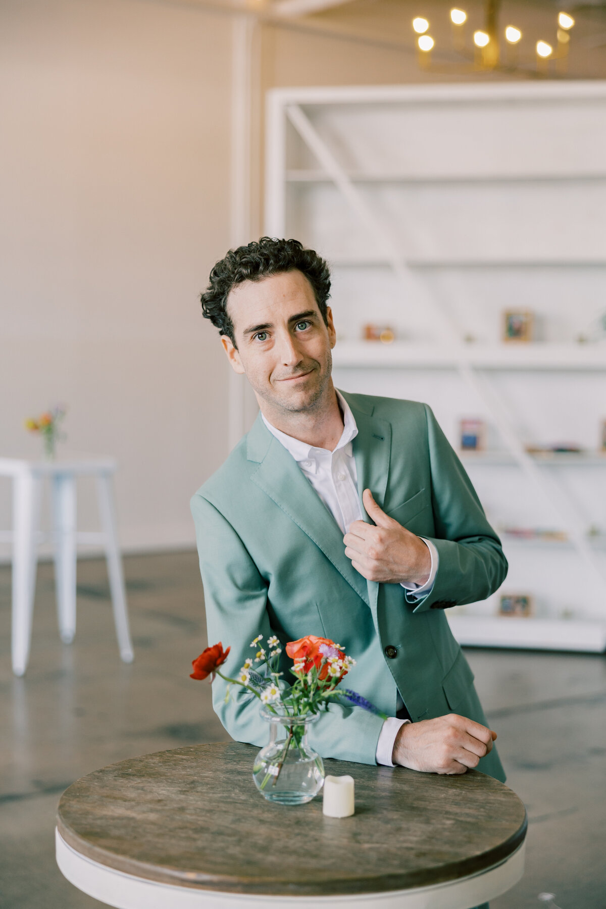 Brendan adjusting jacket in sage Indochino suit before ceremony at Fetewell wedding venue.