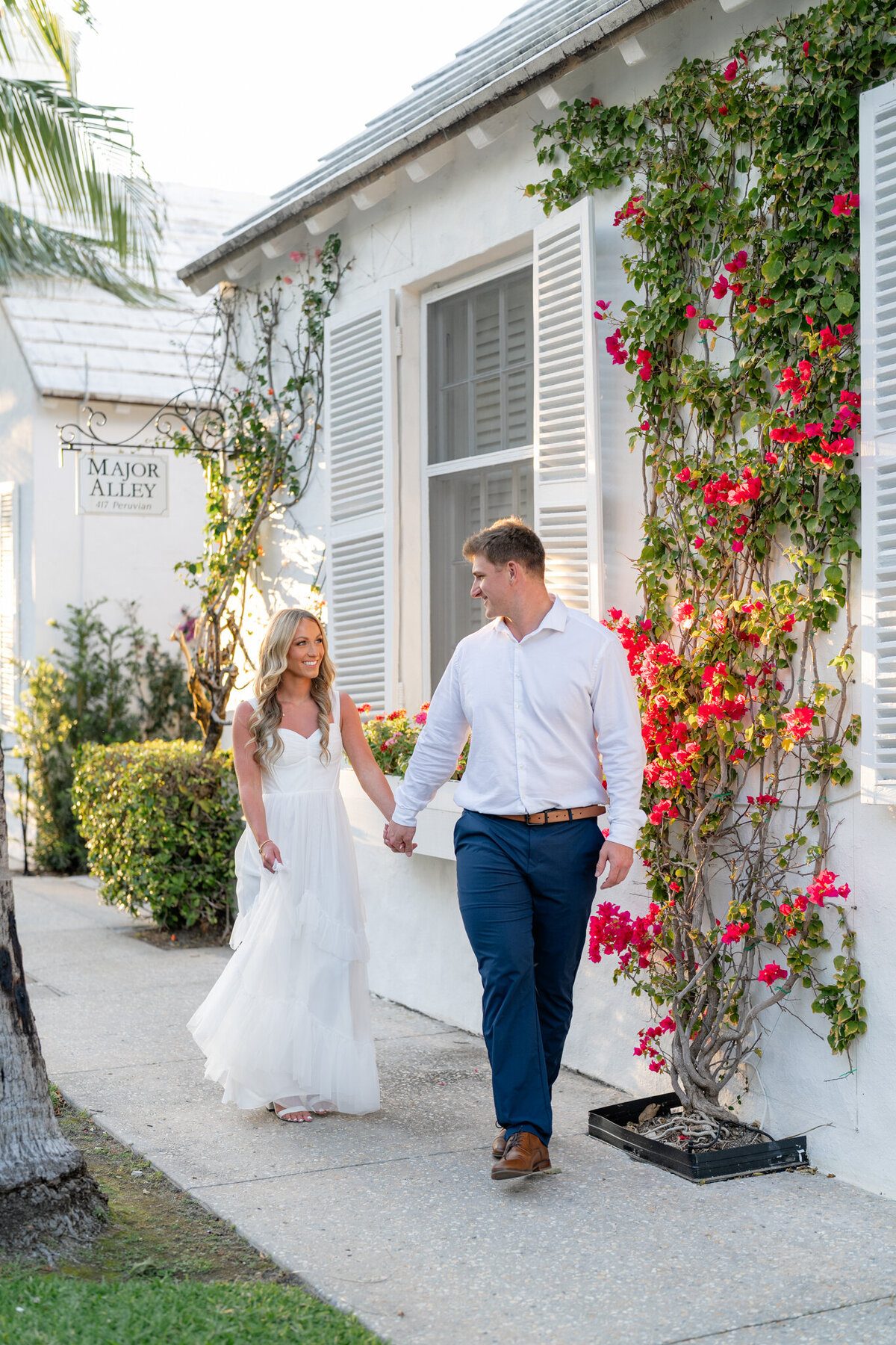 Couple walking hand in hand in front of pretty building & florals