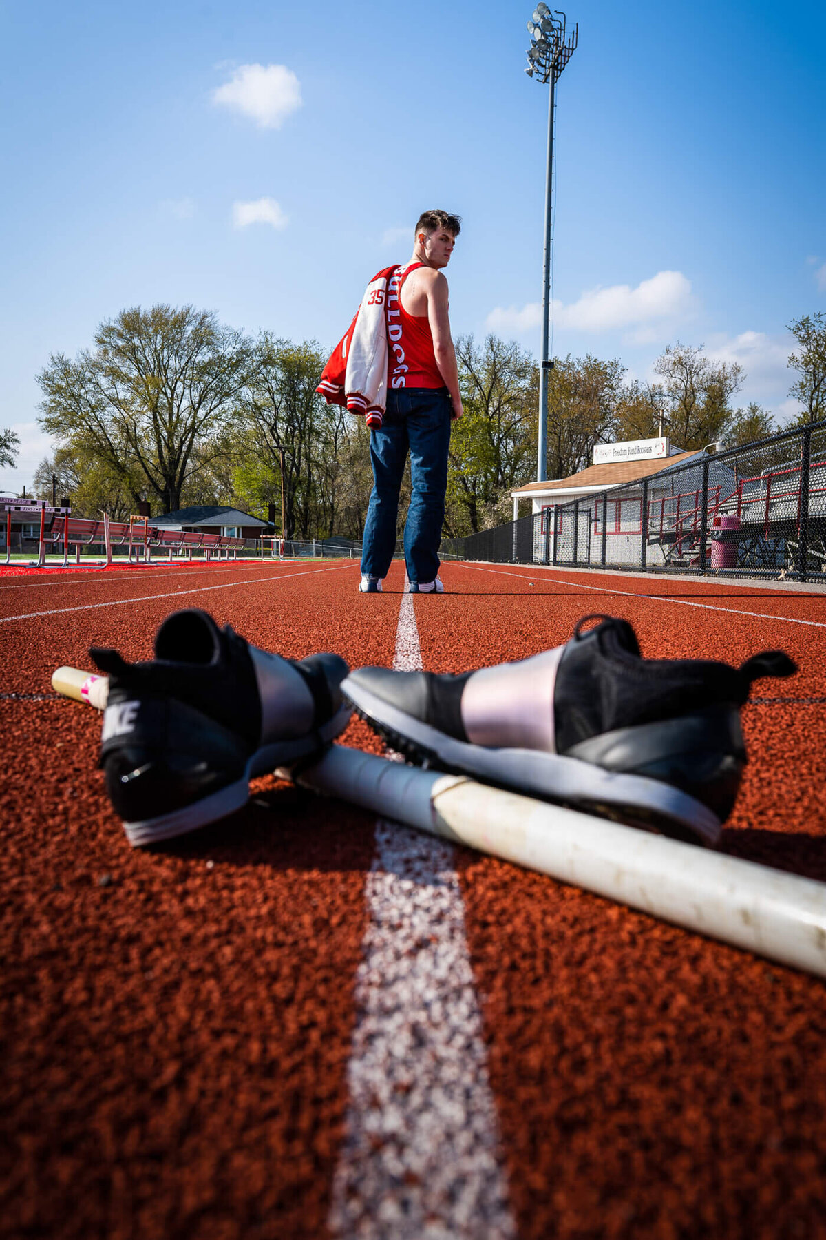 Dramatic senior photo of a senior looking back over his track gear as he walks down his high school track near Freedom PA