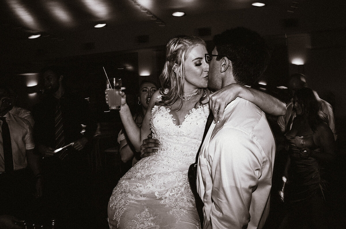 black and white photo of bride and groom kissing during wedding reception