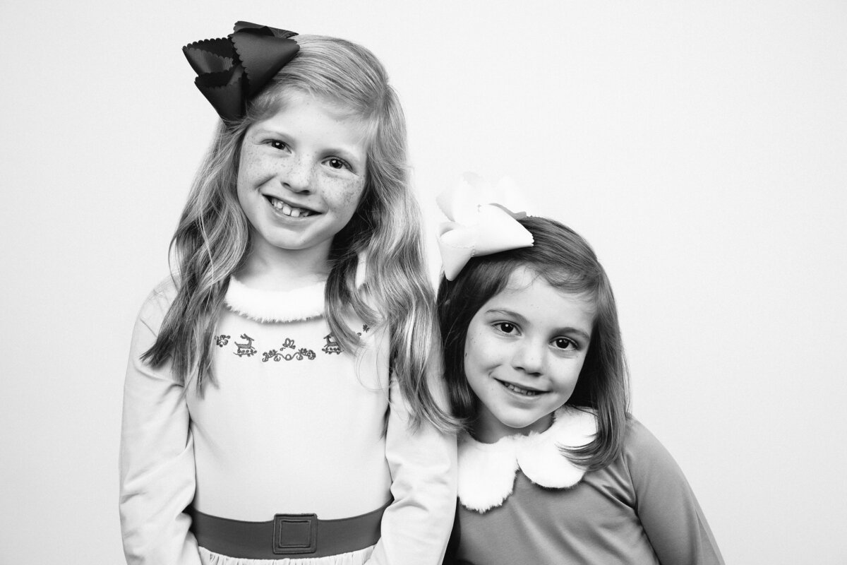 Black and White Holiday Christmas photo featuring two girls wearing Buddy the Elf and Jovie inspired costumes.