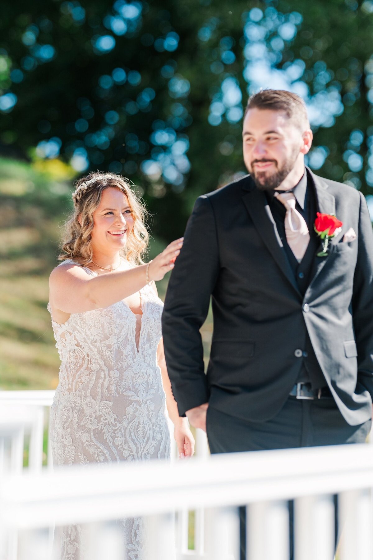 A bride standing behind her groom, tapping him on his shoulder as he begins to turn around. 