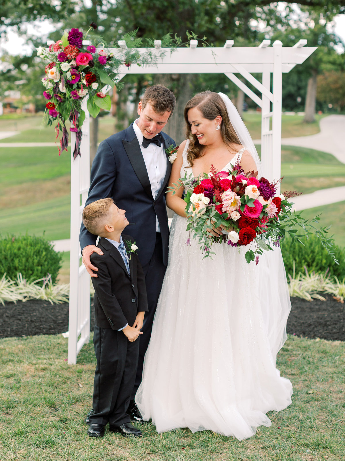 Bride, groom and ringbearer in front of floral arch