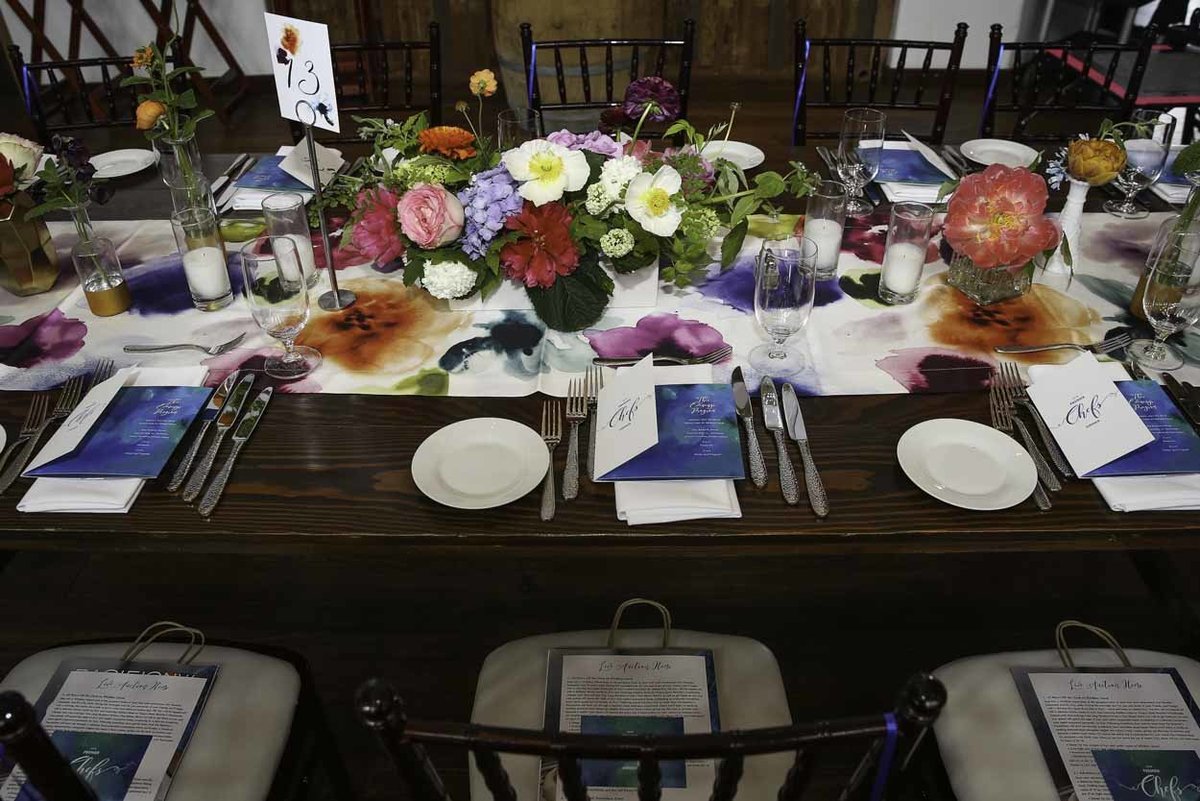 colorful flower centerpiece on colorful linen on long wooden table