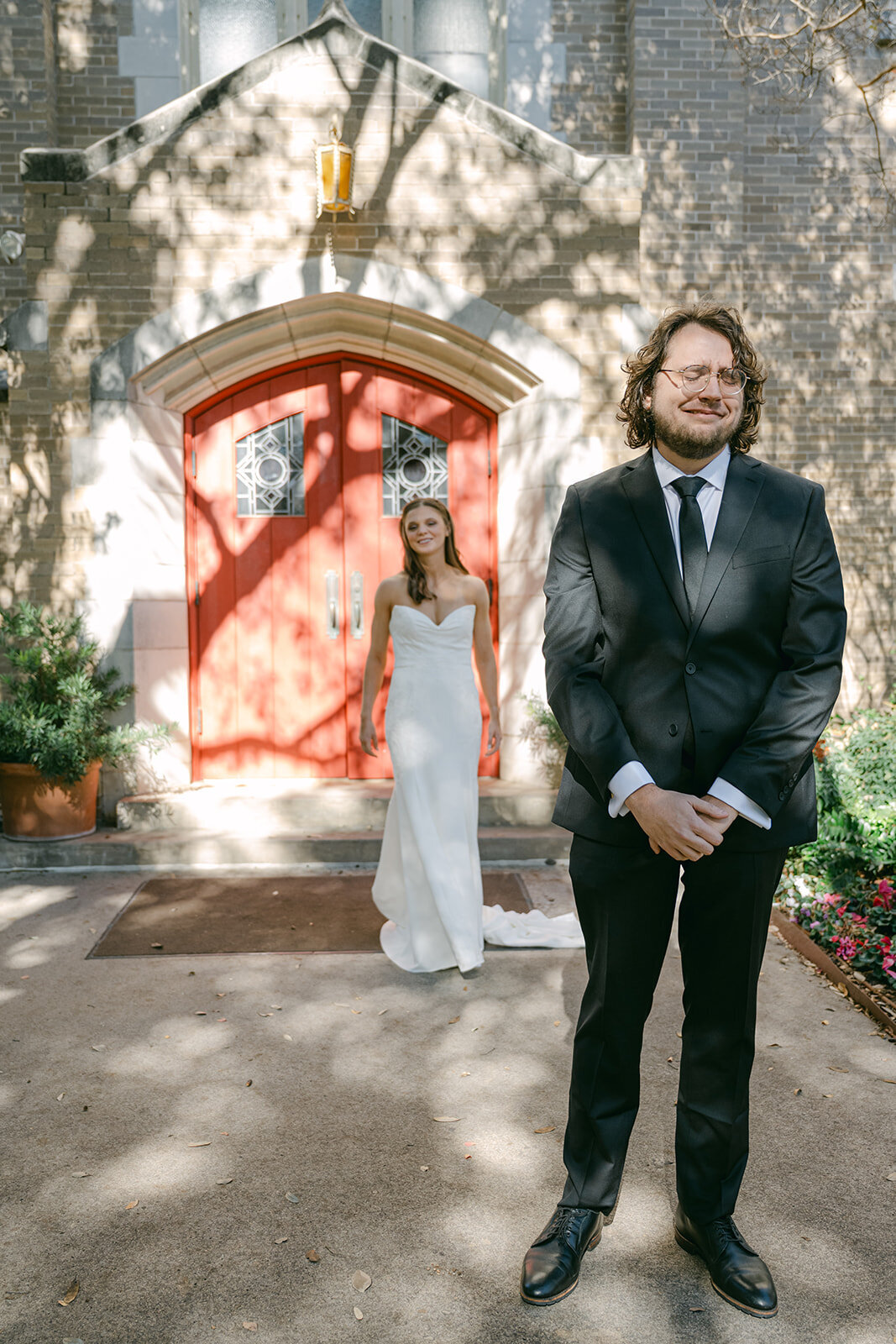 Bride and groom editorial pose under striking red architectural feature at outdoor San Antonio wedding venue