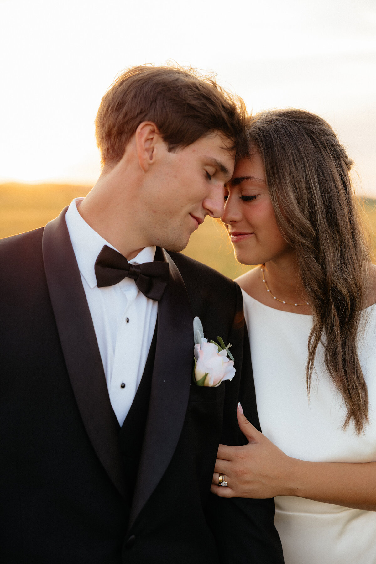 A couple standing forehead to forehead during golden hour on their wedding day.