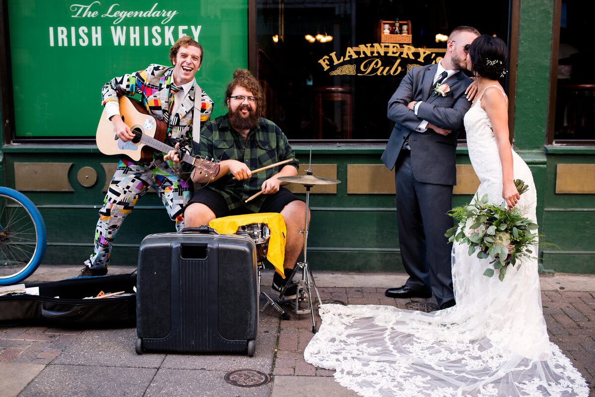 Bride and groom share a kiss next to street performers at Fourth Street restaurant in Cleveland