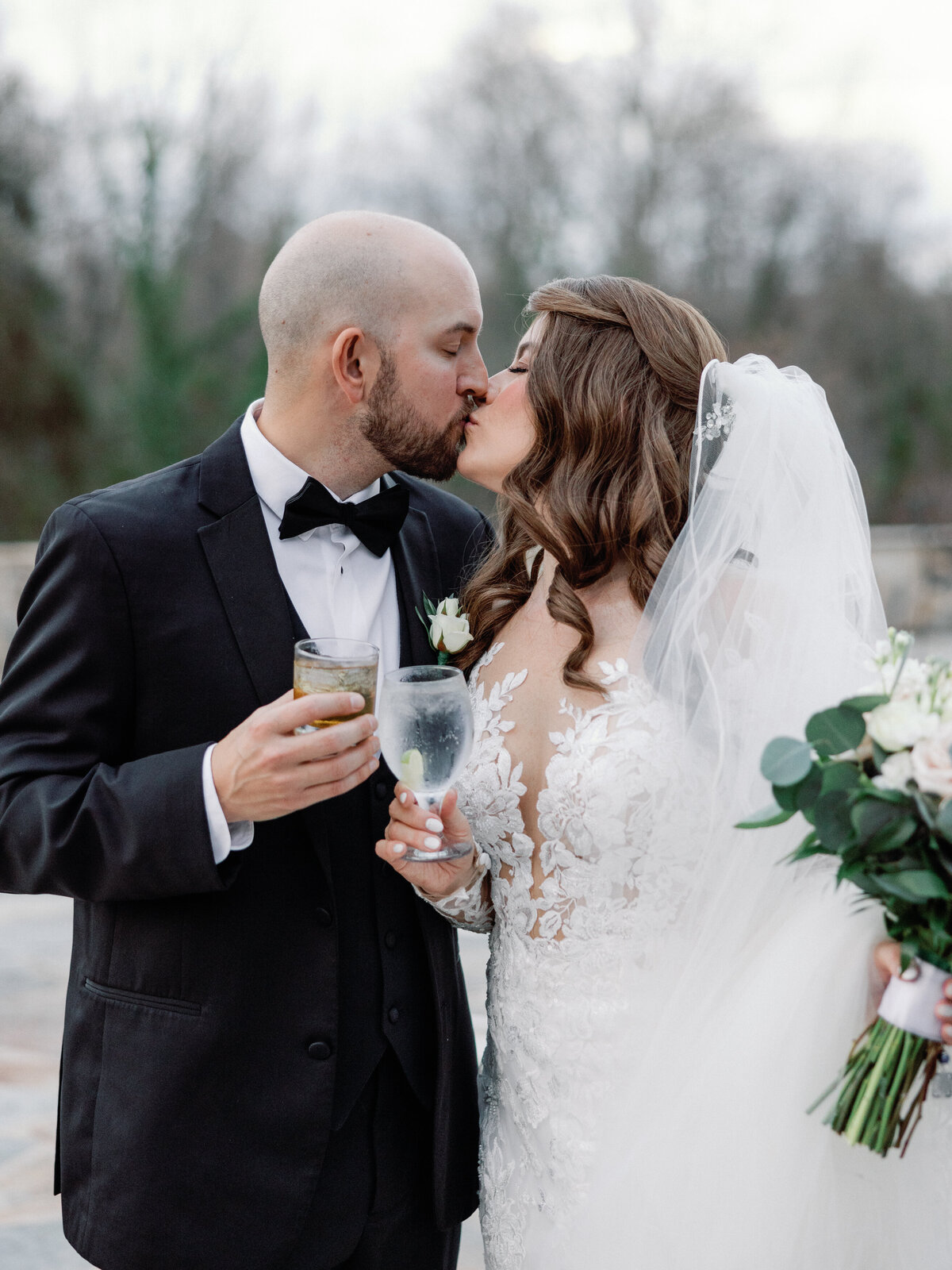 A bride and groom share a kiss as they cheers their signature wedding cocktails