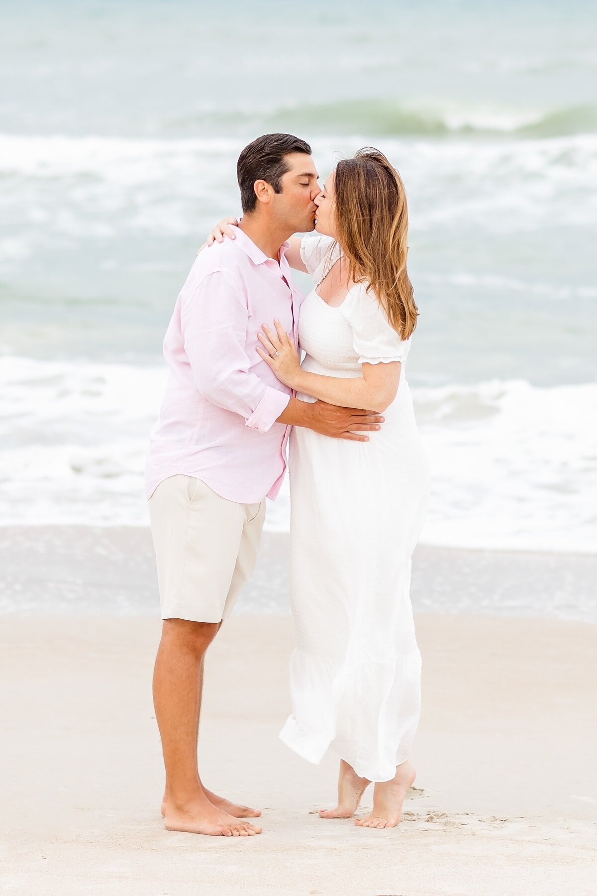 Husband kisses expected wife on the beach