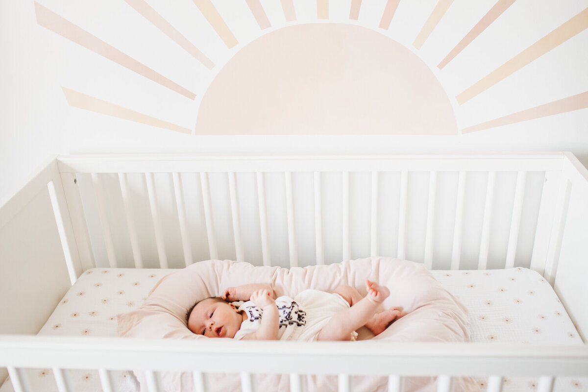 baby girl laying in her crib during her Toronto lifestyle Newborn Photography session
