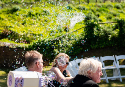 Wedding guests sitting on white chairs with bubbles filling the air