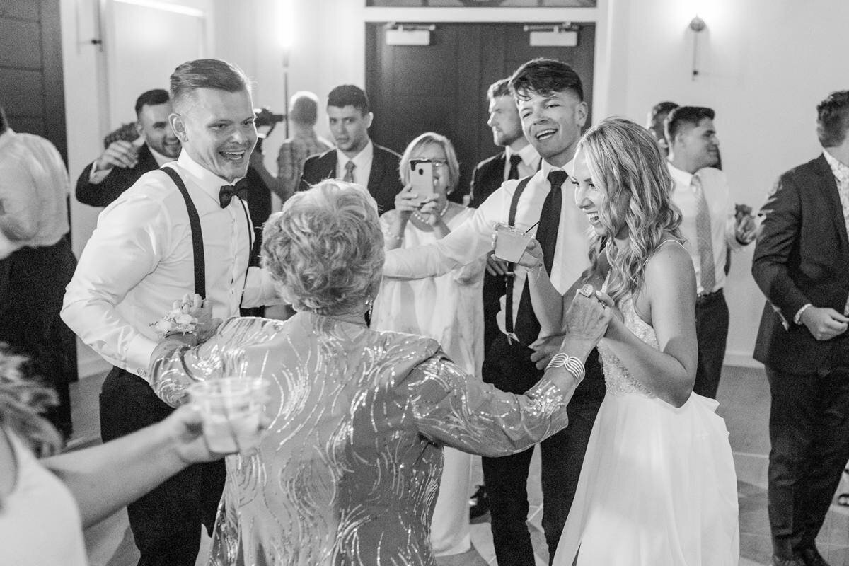 bride and groom pull grandma onto the dance floor