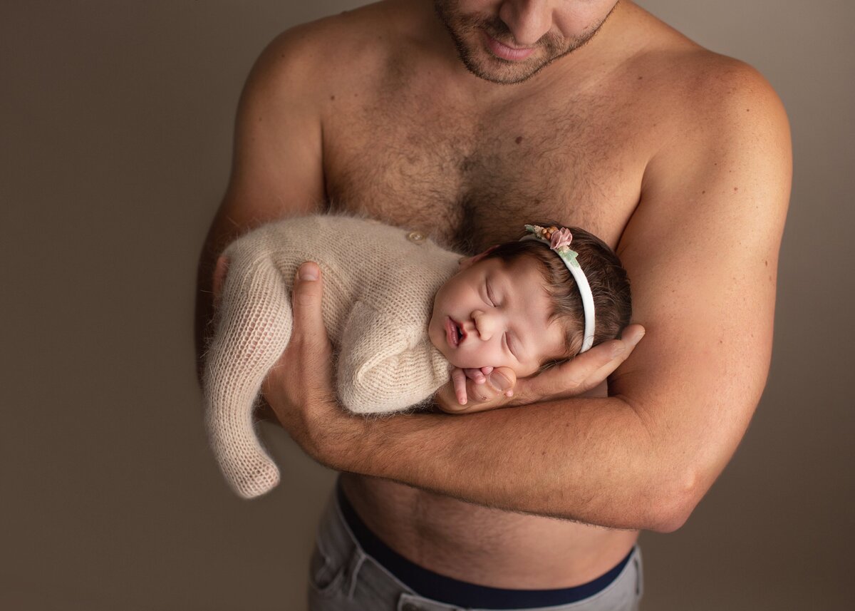 shirtless dad holding his new baby girl in denver studio