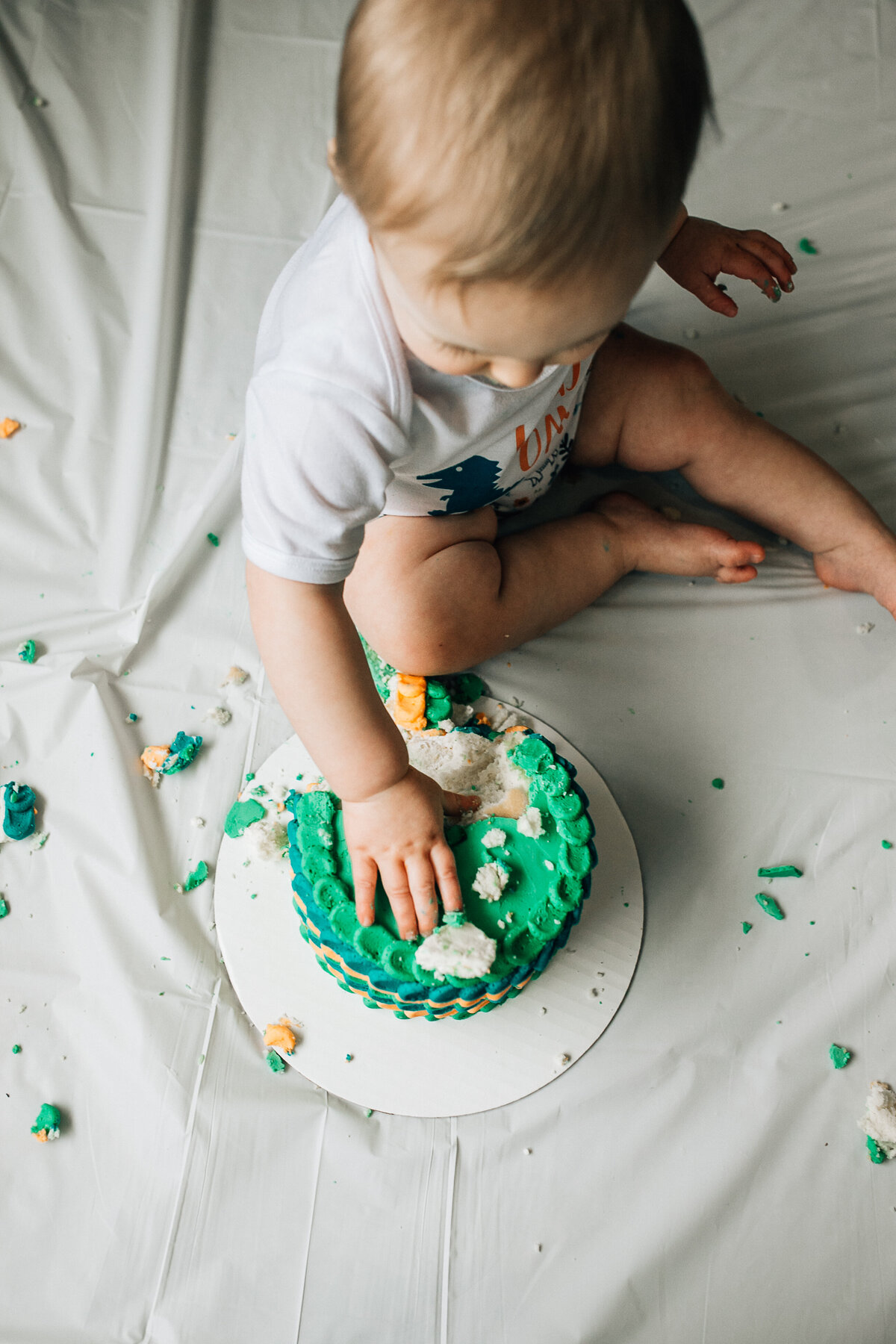 Baby sits on the floor with cake.
