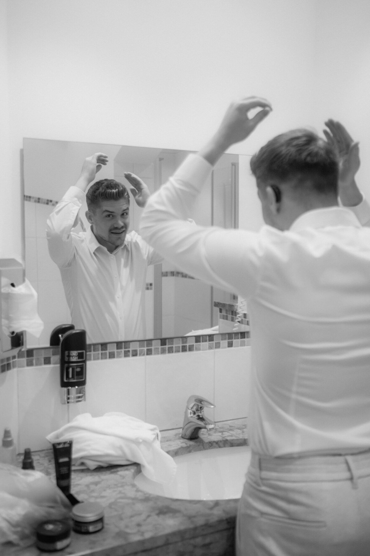 The groom styles his hair for the wedding day during getting ready session.