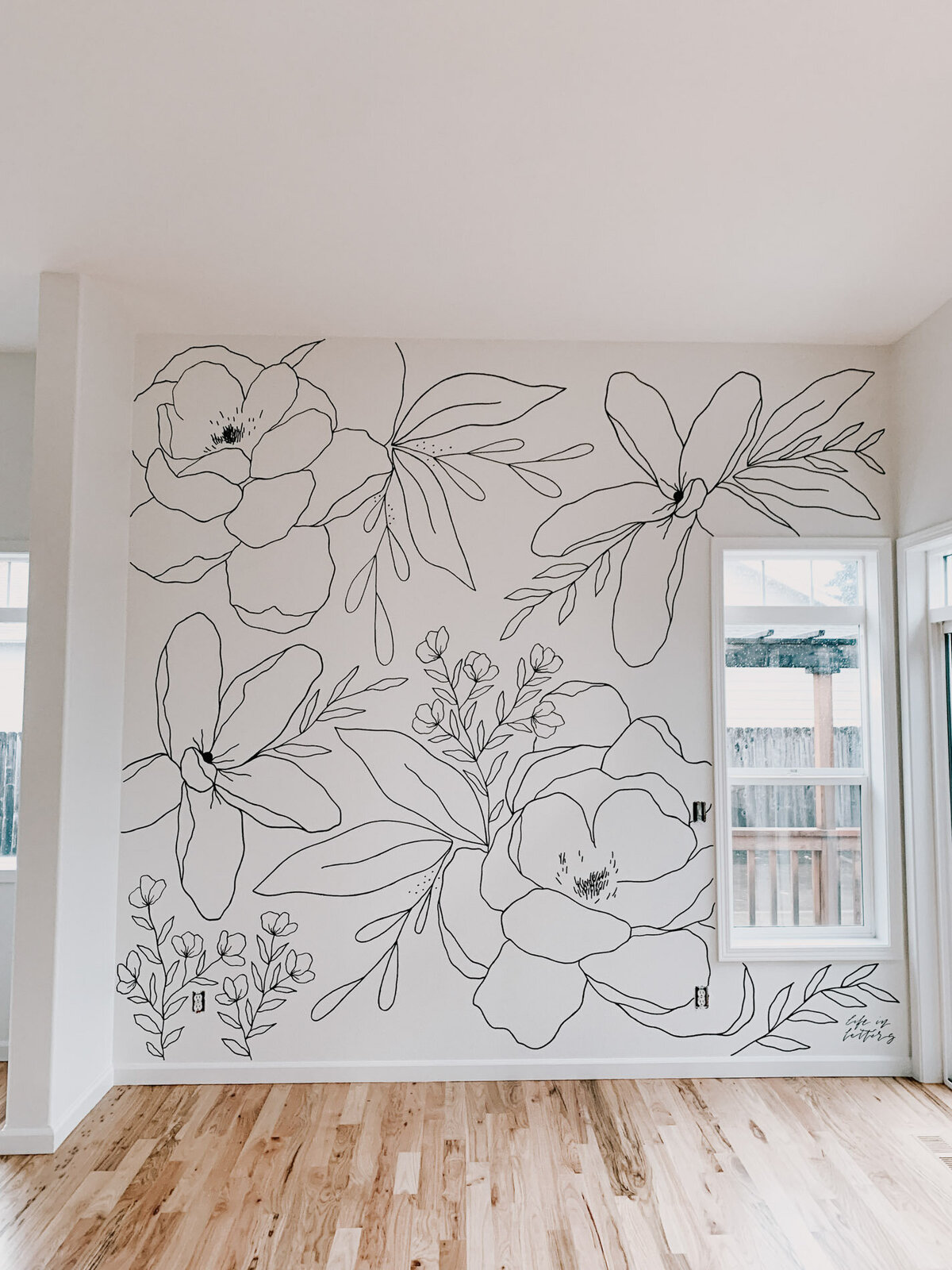A white wall in a dining room with large black and white florals drawn on it representing full service design and calligraphy by Life in Letters.
