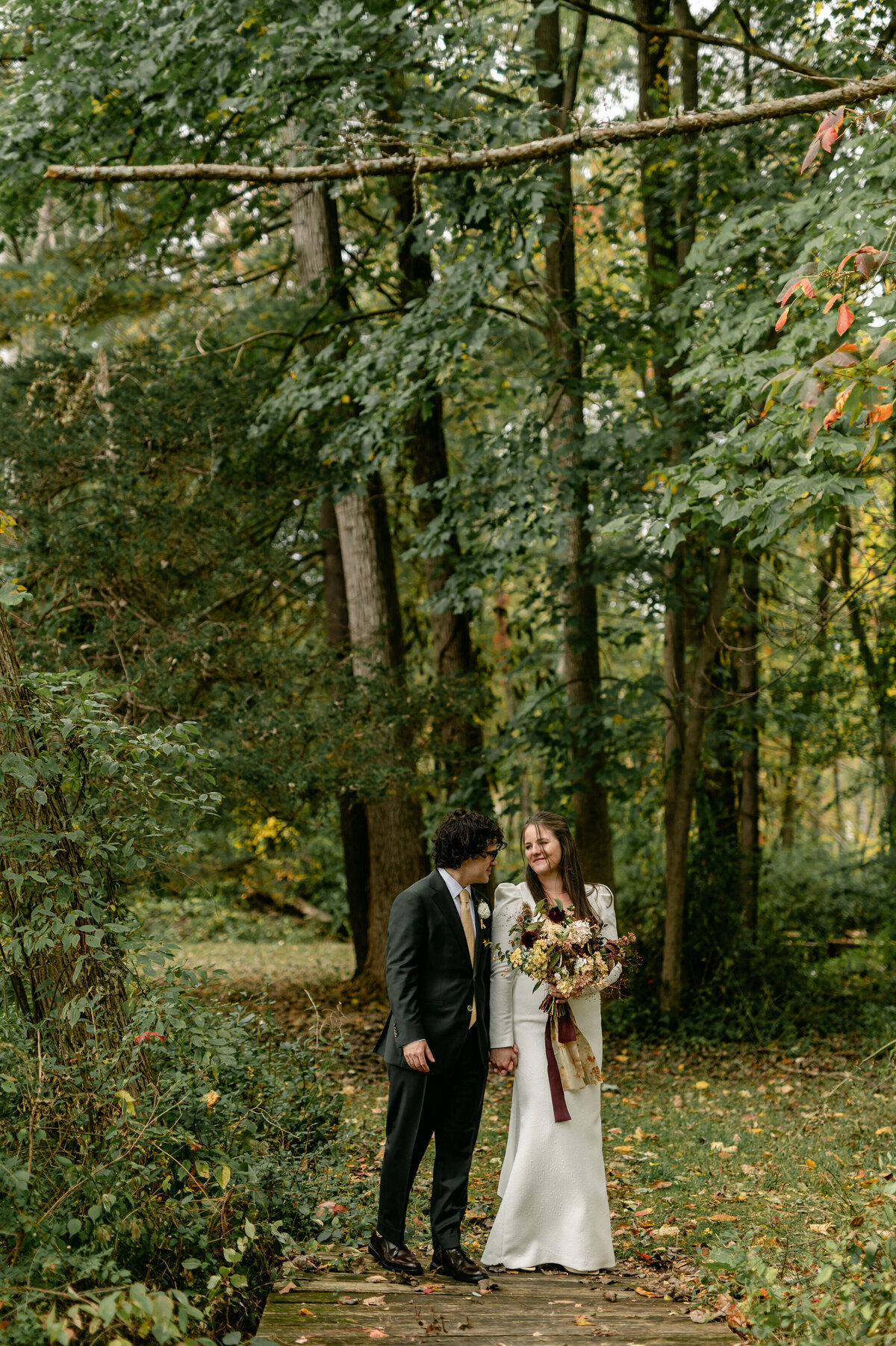 Bride and groom smiling at each other in forest