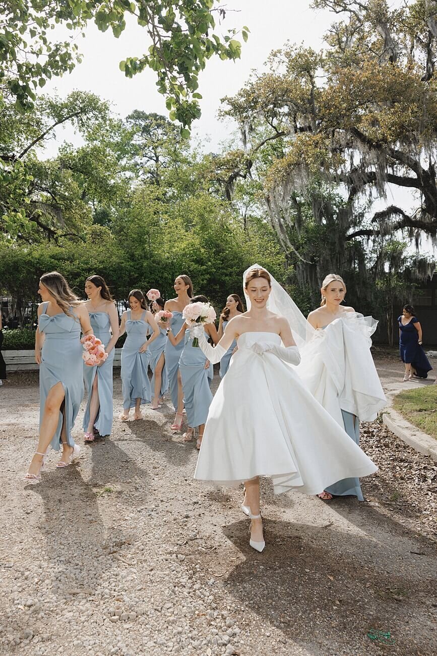 bride and bridesmaids walking under trees