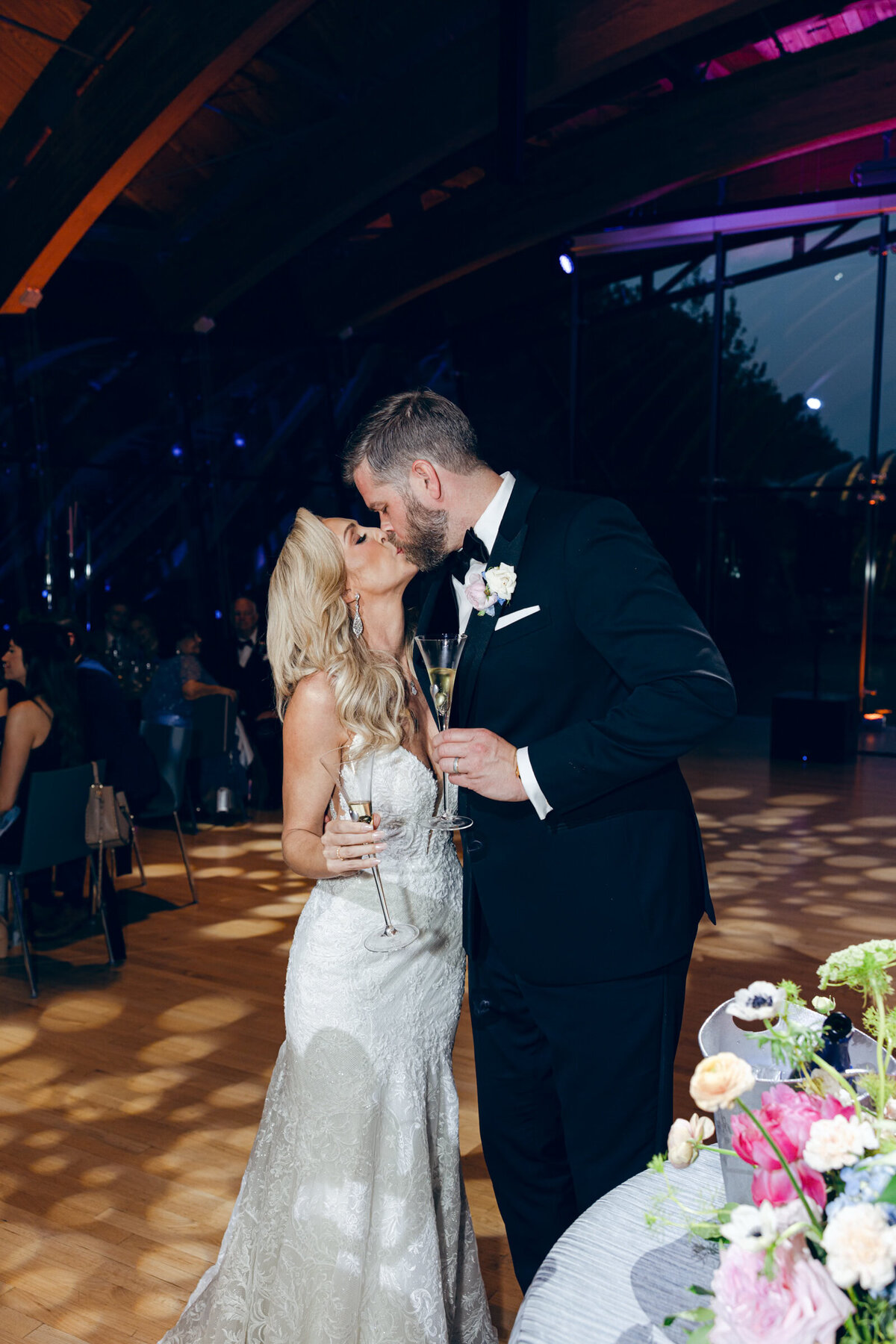 A candid wedding day photo of the bride and groom kissing after cutting their wedding cake at Crystal Bridges Museum of American Art