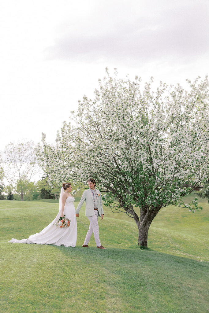 Bride and Groom walking the property of Sugar Pine Island, a romantic wedding venue in Foothills, Alberta, featured on the Brontë Bride Vendor Guide.