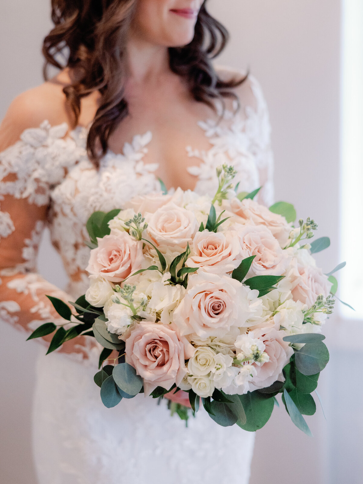 A closeup of the bride holding her bouquet of blush pink and white florals