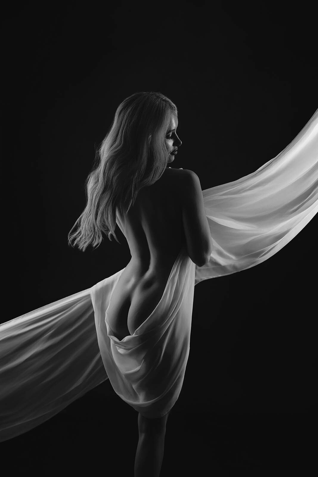 Hidden by long flowy fabric a woman is posed for a Vancouver Boudoir Photographer