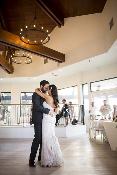 A bride and groom stand forehead-to-forehead as they share their first dance under the wooden beam ceiling at The Oaks at Plum Creek in Castle Rock, Colorado.