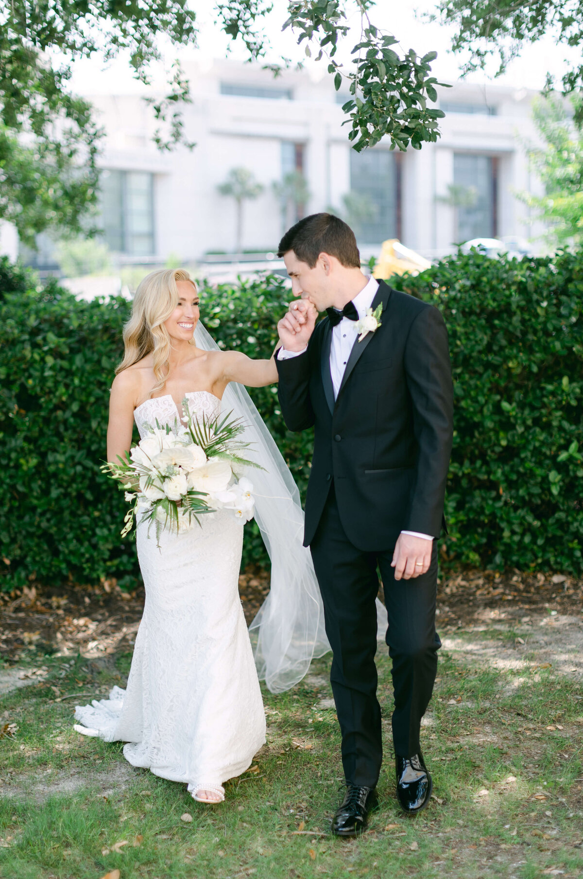 A groom kisses his brides hand.
