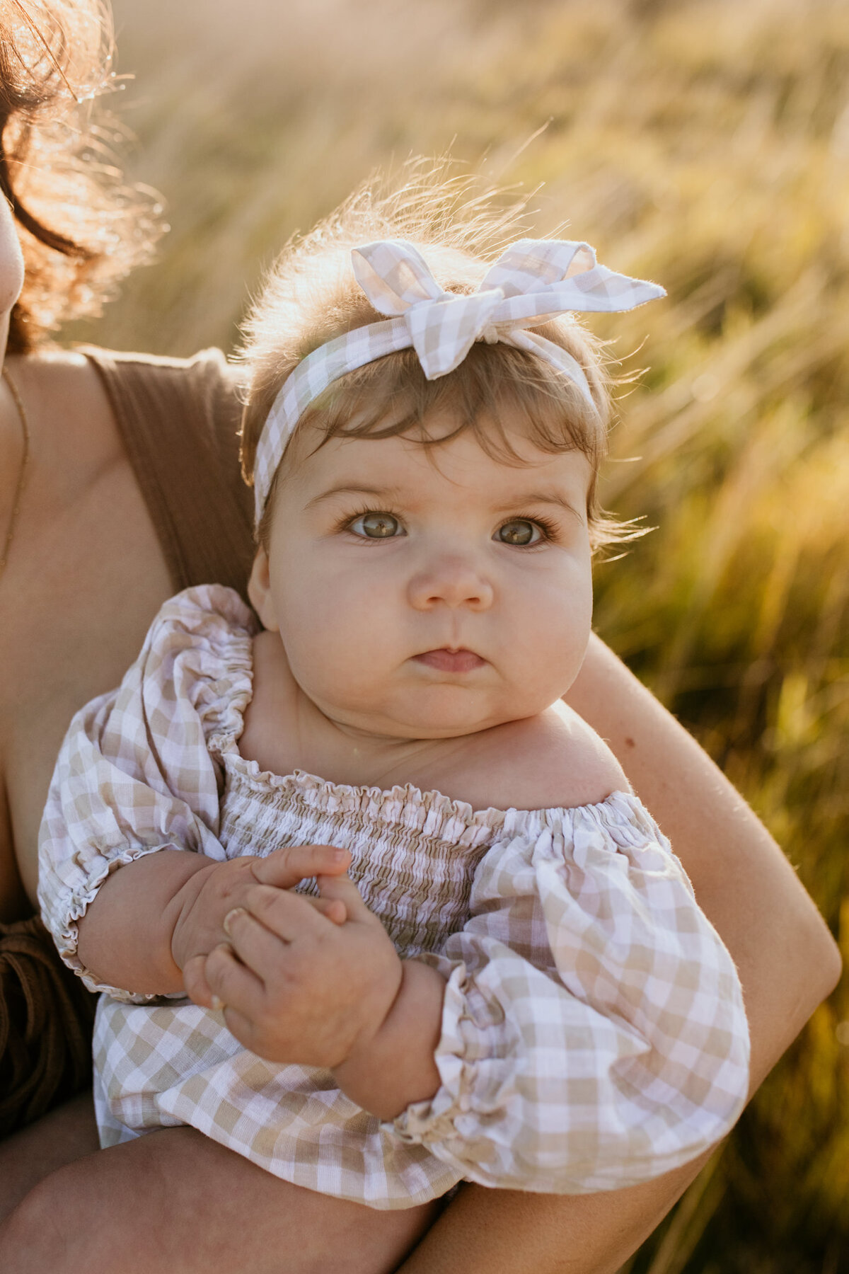 Baby girl with a checker outfit looks up to the camera. 