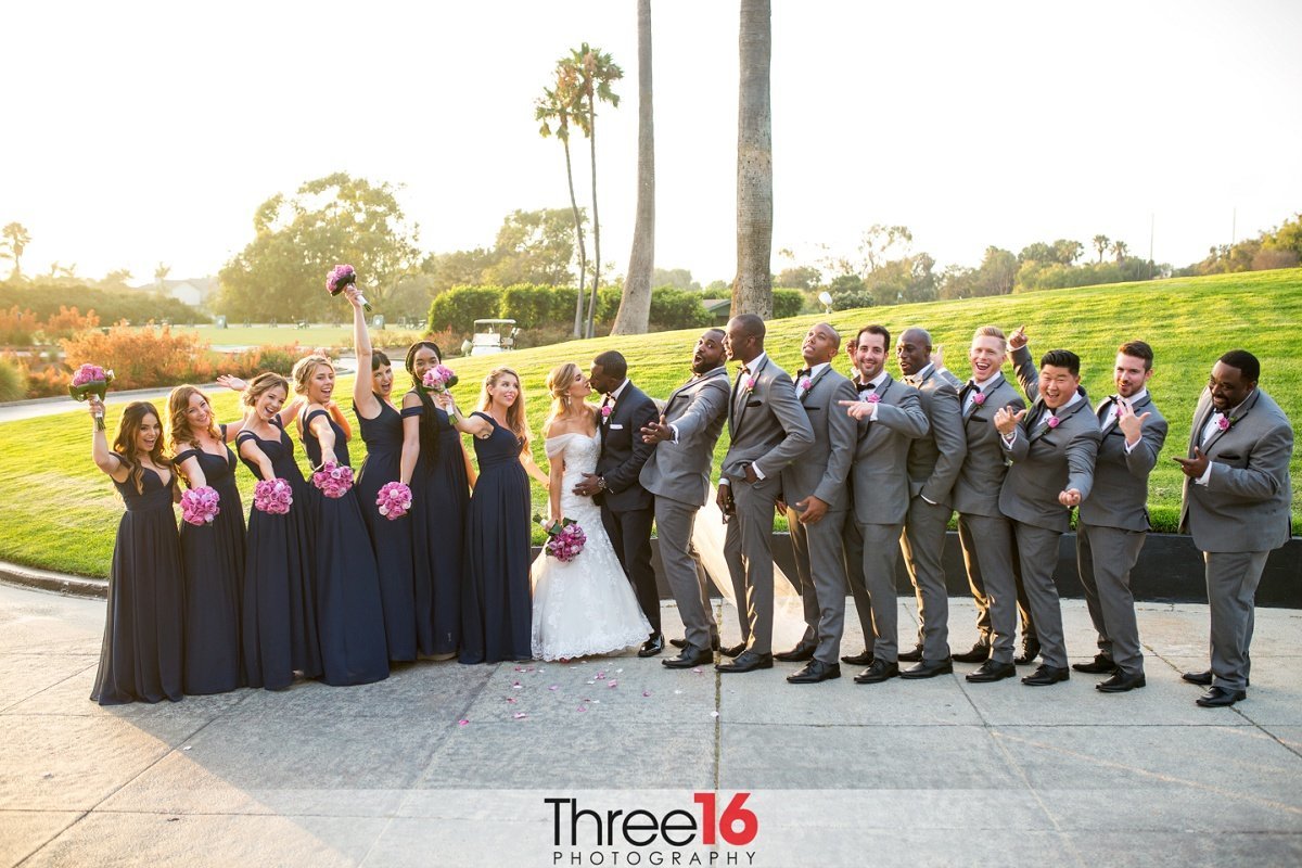 Bridal Party cheers as Bride and Groom share a kiss
