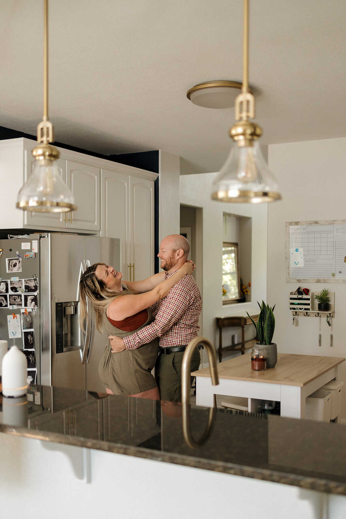 Expectant-mom-and-dad-dancing-in-the-kitchen-laughing-in-longmont-colorado