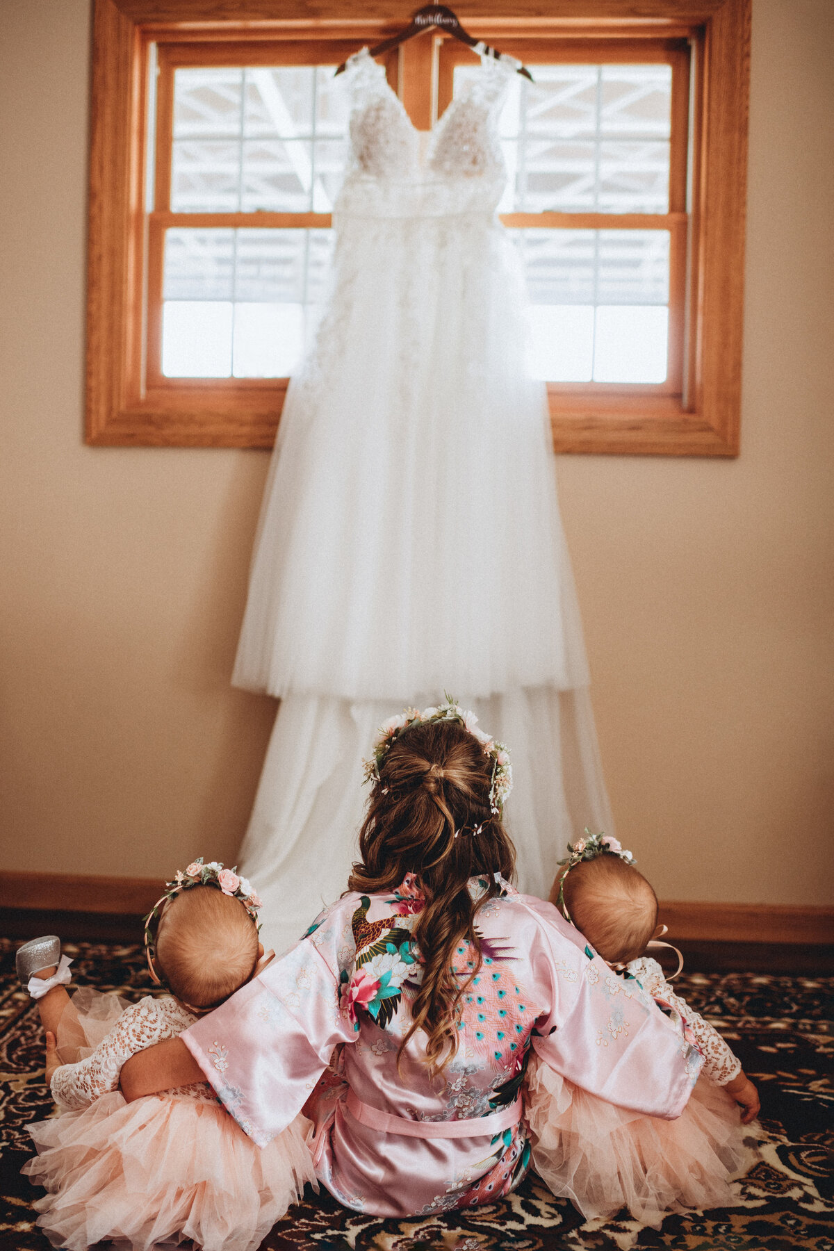 Three little girls sitting and looking up at wedding dress