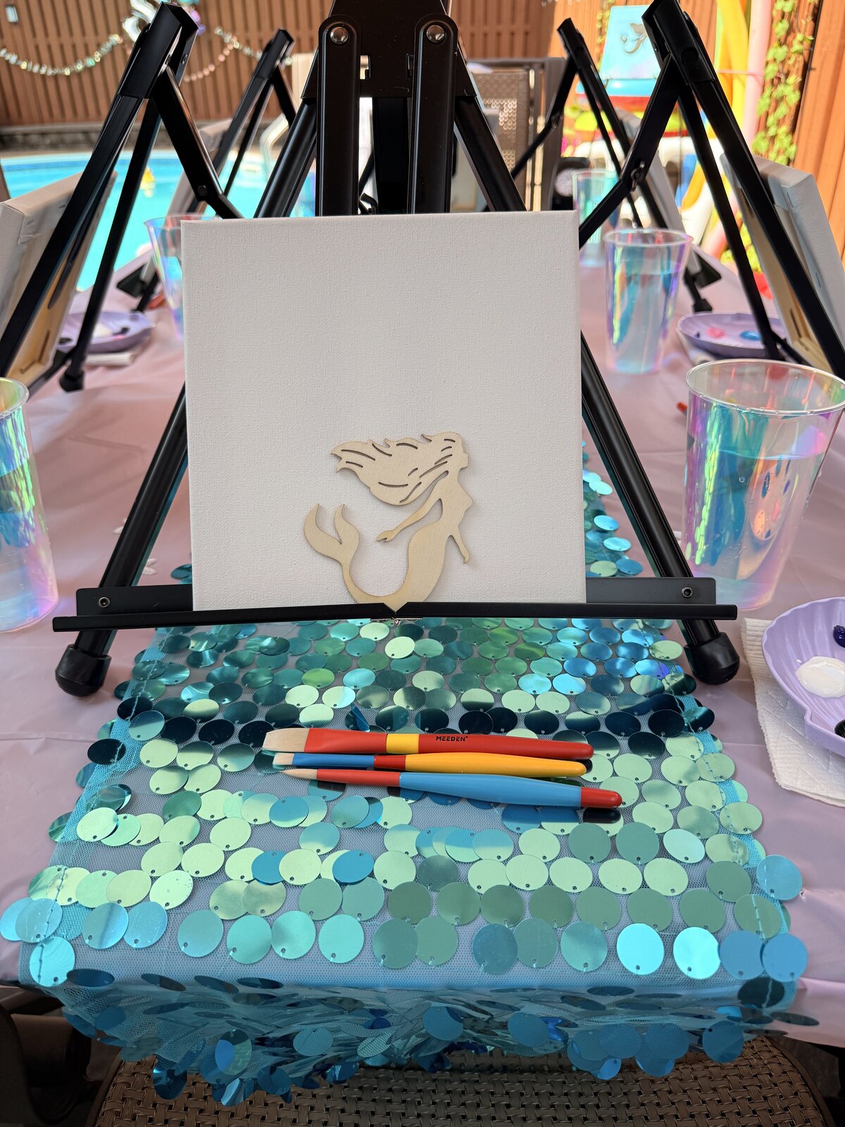 Mermaid-themed birthday party table set up with paint supplies, bubbles, and themed decorations by Young at Art