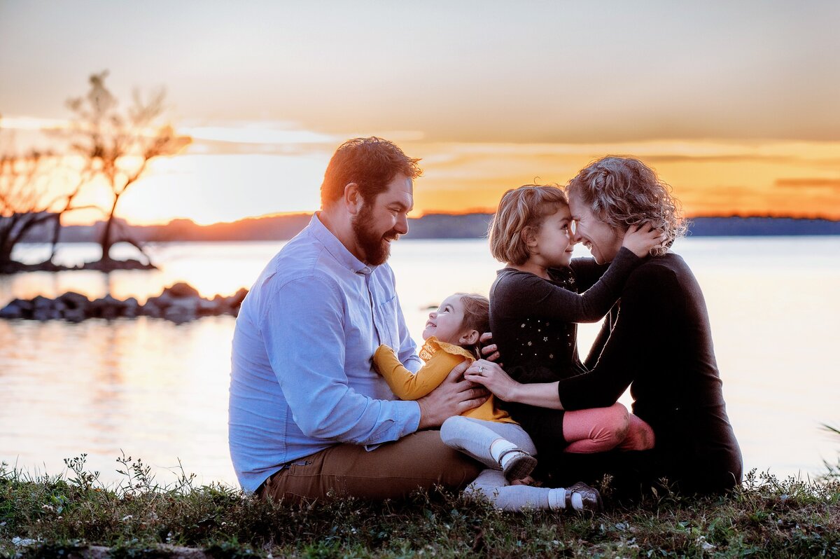 Family cuddle along the lakeshore at sunset