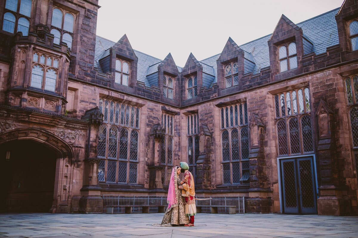 A sikh wedding couple standing inside the east pyne hall with beautiful gothic architecture at princeton university 