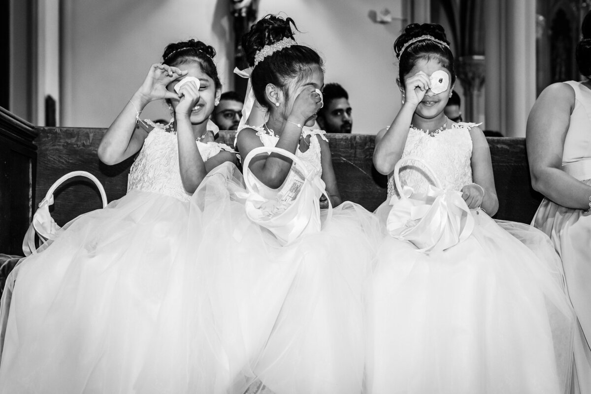 A group of young flower girls sits and poses together at a wedding ceremony
