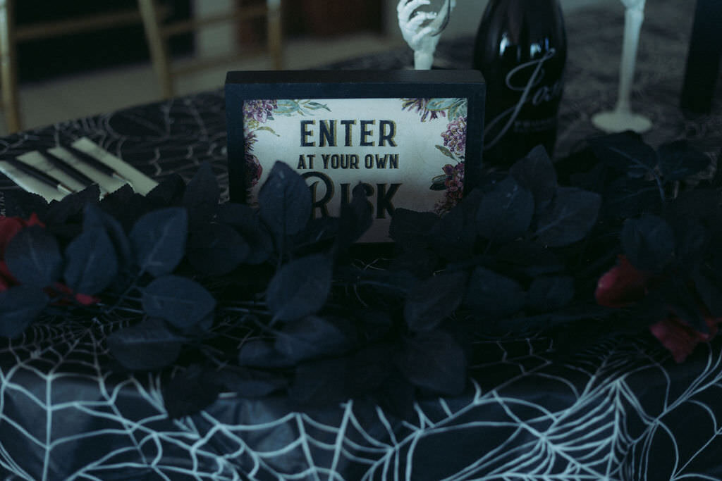 A flowered covered table with a sign that reads "enter at your own risk"