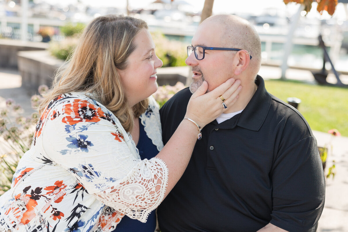 A married couple is looking at each other lovingly while seated in a park