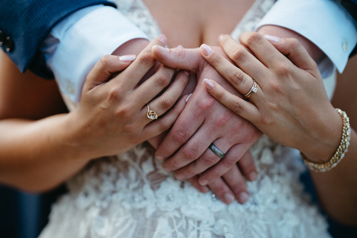 A close up of two people arms around each other showing off wedding rings 
